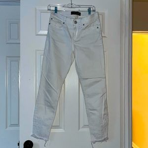 Express white denim with embroidery detail & raw hem.